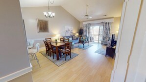 A spacious living area with a dining table, sofas, and a TV. - Myrtle Beach Golf Villa | Pool View | Blocks to Beach | Magnolia Place 4679-303 (Myrtle Beach)