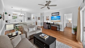A modern living room with a sofa, coffee table, and a dining area with a table and chairs. - Morning sun | golf fun | ocean breeze retreat | Magnolia Place 4701-103 (Myrtle Beach)