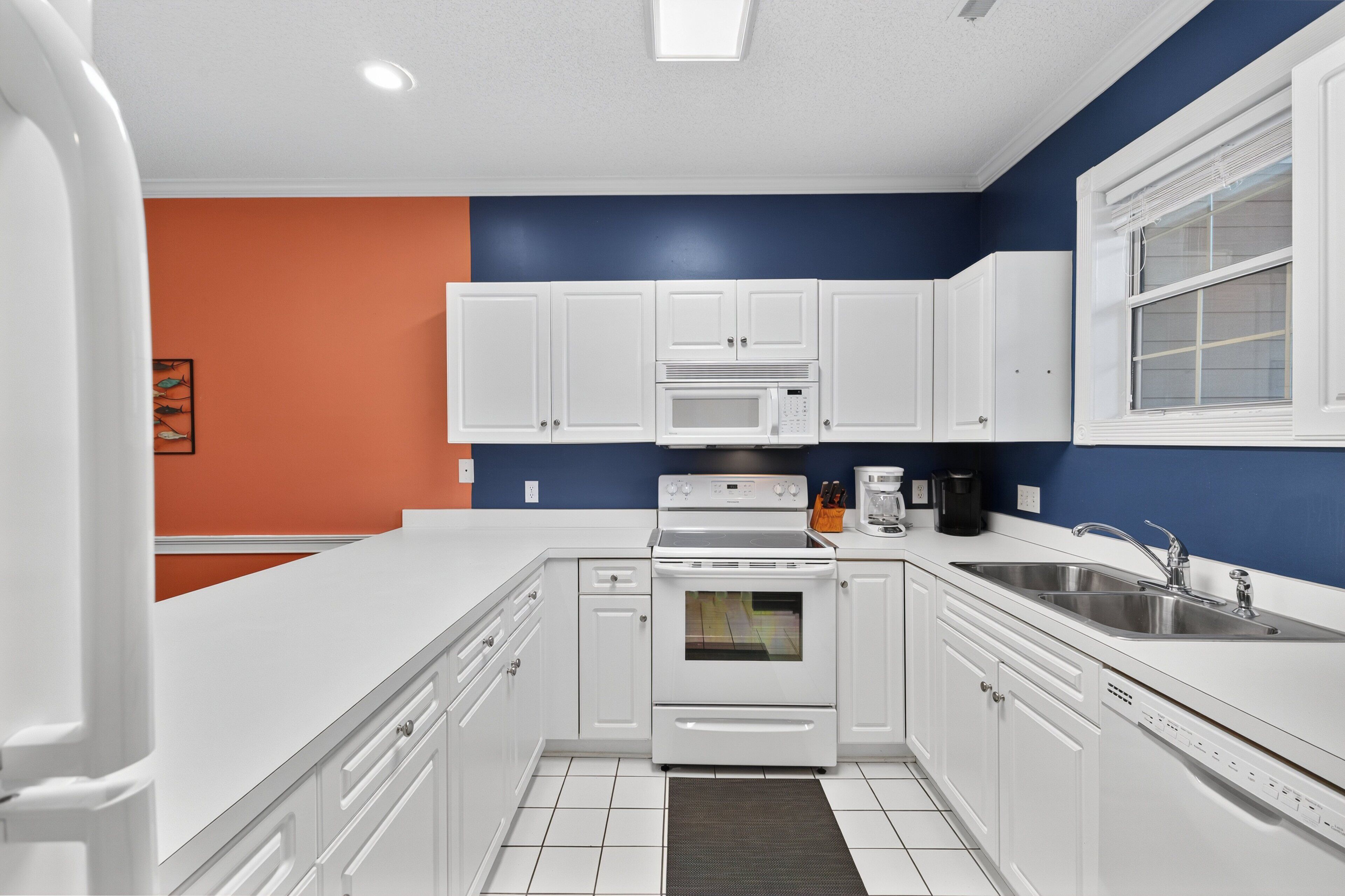 A modern kitchen with white cabinets, a microwave, an oven, and a sink.