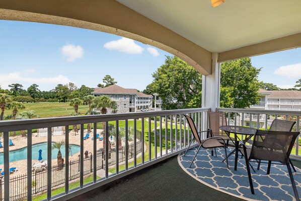 A balcony with a view of a swimming pool and a golf course. - Myrtle Beach Golf Villa | Pool View | Blocks Away | Magnolia Place 4773-304 (Myrtle Beach)