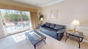 A living room with a black leather sofa, a glass coffee table, and two side tables with lamps. - Escape to Nature | Pool & Golf Views | Magnolia Pointe 4877-104 (Myrtle Beach)