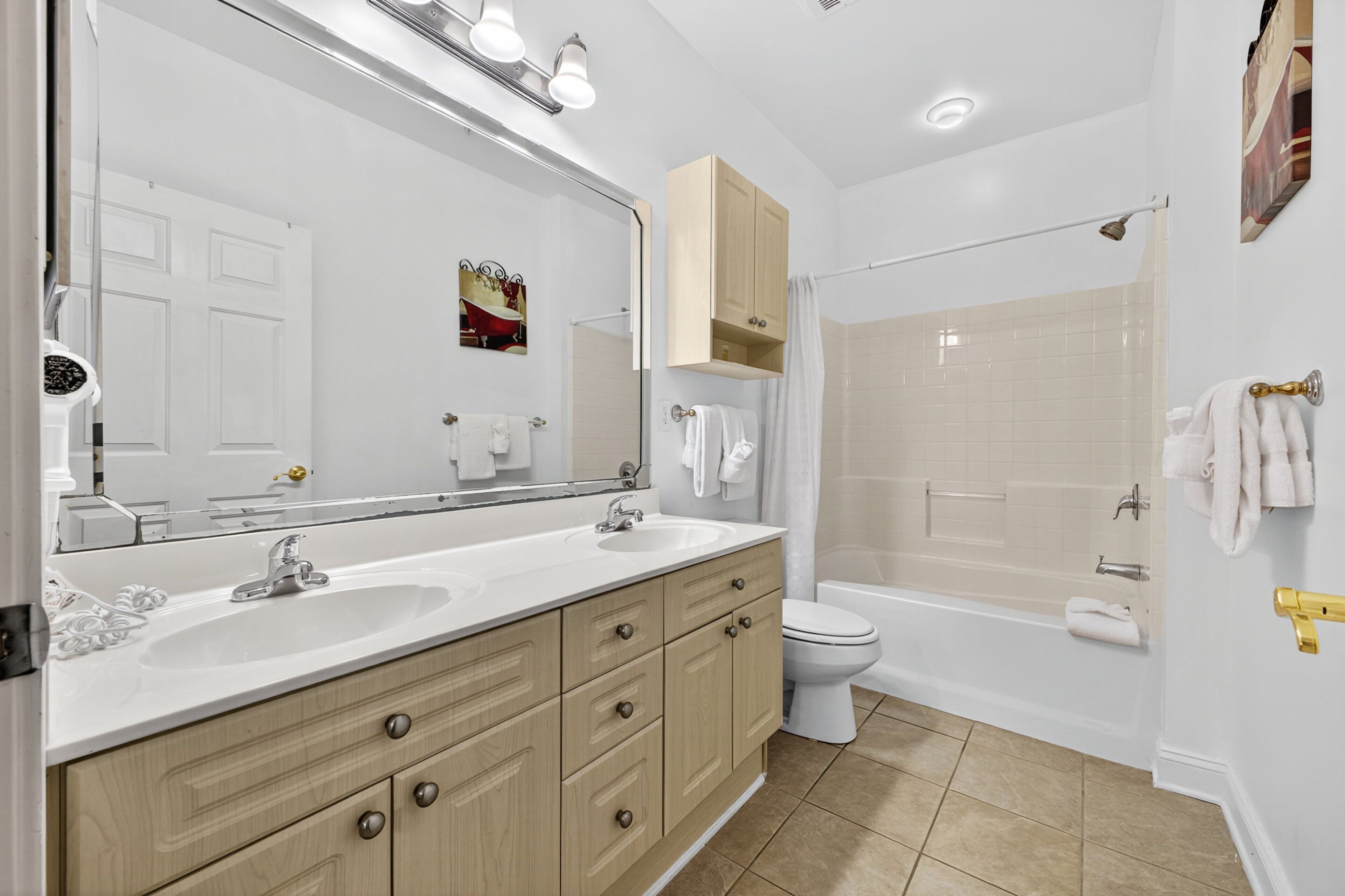 A modern bathroom with two sinks, a toilet, and a bathtub.