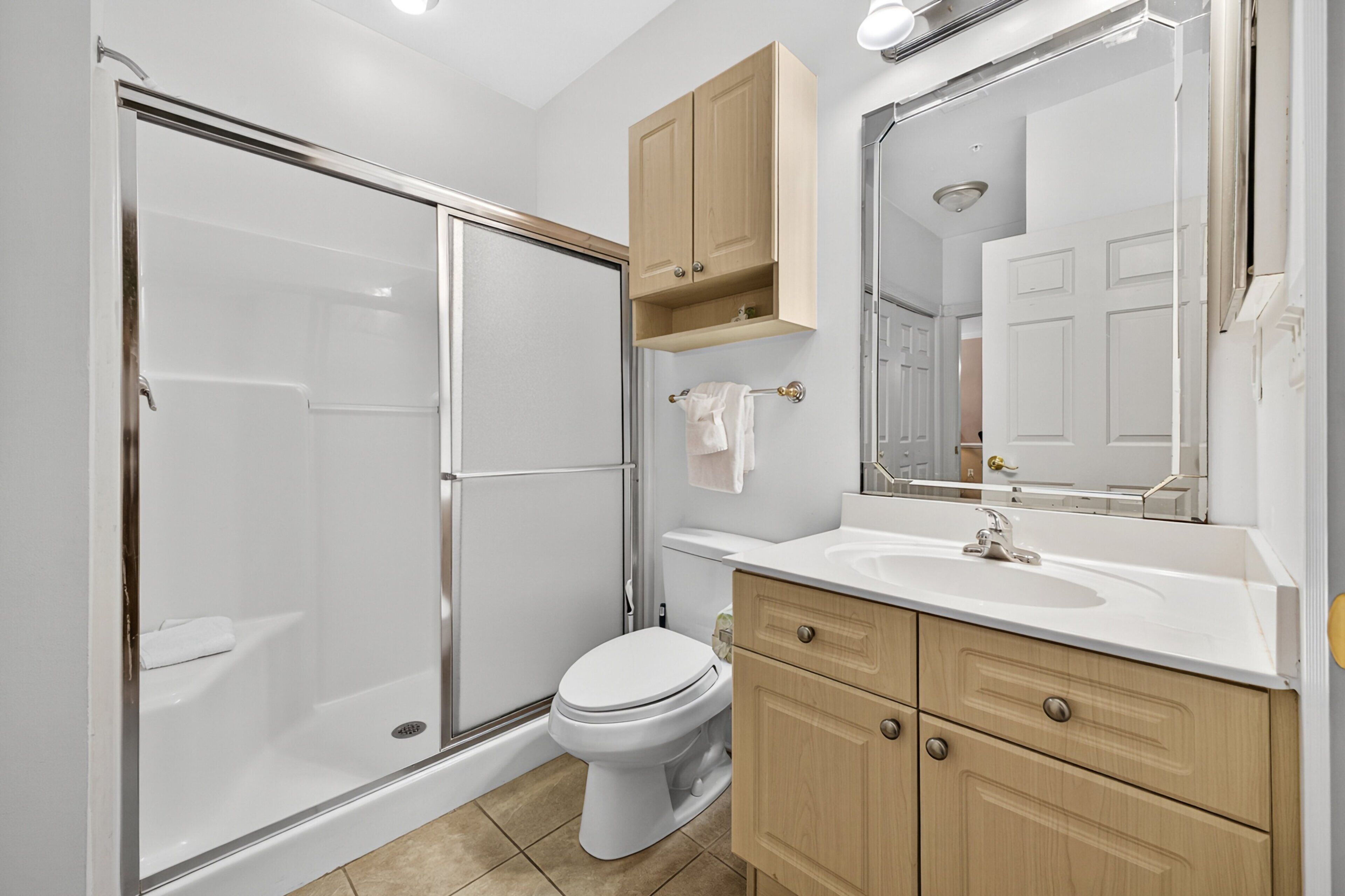 A modern bathroom with a glass-enclosed shower, a toilet, and wooden cabinets.