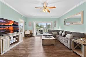 A living room with a television, a ceiling fan, a sofa, and a coffee table. - Unwind in Nature | Pool & Golf Course Views | Magnolia Pointe Luster Leaf 4890-303 (Myrtle Beach)