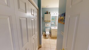 A bathroom with a toilet, sink, and cabinets.