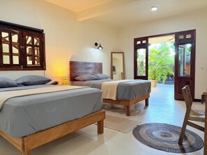 A bedroom with two beds, a nightstand, a mirror, and a view of the outdoors.