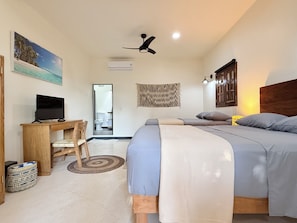 A bedroom with a bed, a desk, a chair, a television, and a ceiling fan.