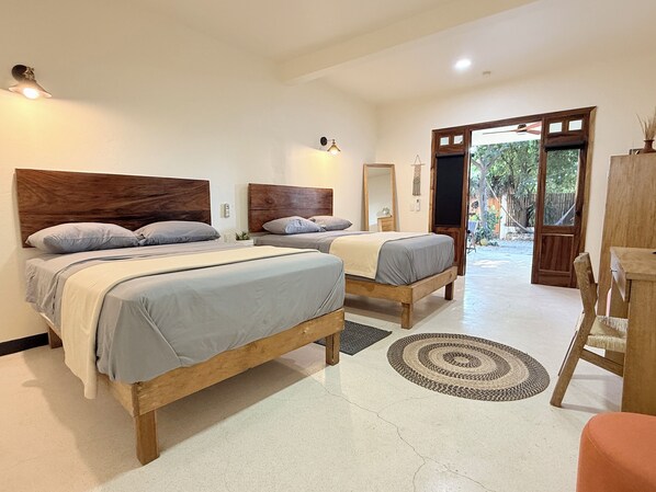 A bedroom with two wooden beds, a wooden nightstand, a mirror, and a door leading to an outdoor area.