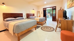 A hotel room with two beds, a desk, a television, and a view of the outside.