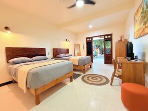 Habitación de hotel con dos camas, un escritorio, televisión y vista al exterior.