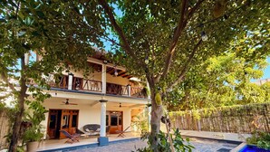 A two-story building with a balcony, outdoor seating area, and a tree with fruit.