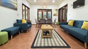 A living room with two sofas, a coffee table, and a dining area with chairs and a table.