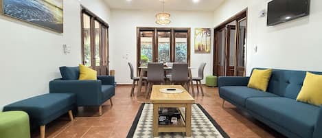 A living room with two sofas, a coffee table, and a dining area with chairs and a table.