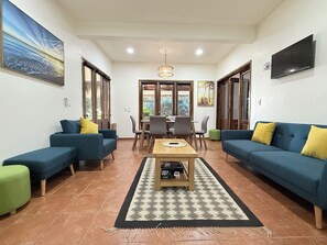 Una sala de estar con dos sofás, una mesita de centro y una zona de comedor con sillas y una mesa.