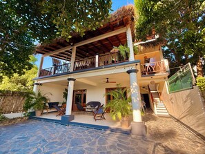 A two-story building with a covered patio, outdoor seating, and a staircase leading to the upper level.