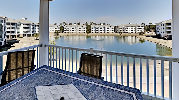 A balcony with a view of a calm lake, surrounded by multi-story buildings. - Magnolia Pointe Retreat Near the Beach | Magnolia Pointe Magnolia Lake 4812-201 (Myrtle Beach)