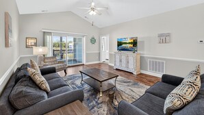 A spacious living room with a ceiling fan, a large window with a view, a flat-screen TV, and a fireplace. - Bright and Inviting Magnolia Pointe Lakefront Condo | Magnolia Pointe Magnolia Lake 4828-402 (Myrtle Beach)
