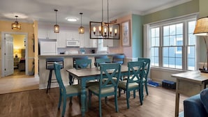 A kitchen with teal chairs, a wooden dining table, and pendant lights.