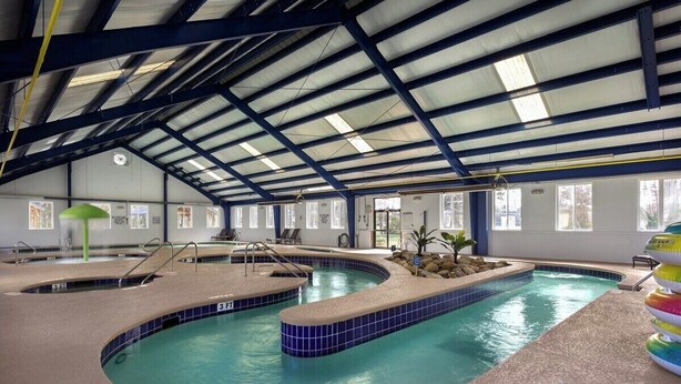 An indoor swimming pool with a curved design, multiple lanes, and a covered roof structure.