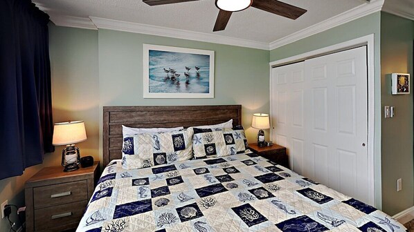 A bedroom with a wooden headboard, a quilted bedspread, two bedside lamps, and a ceiling fan. - SBC | Beautiful 2BR | Oceanfront Condo | w/ pools! | SBC 515 (Myrtle Beach)