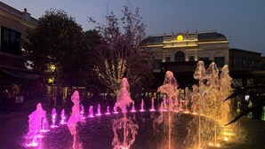 Un spectacle nocturne de jets d’eau, avec de nombreux jets illuminés de couleurs rose et jaune.