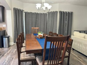 A dining room with a wooden table, chairs, a chandelier, and curtains. - Family-Friendly Stylish 5BR w/ Theater & Hot Tub in Meridian Idaho (Meridian)