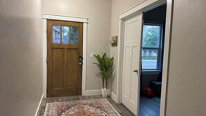 Un couloir avec une porte en bois, une porte blanche et un tapis à motifs.
