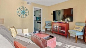 A living room with a sofa, a coffee table, a red cabinet, and a television.