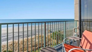 A balcony with a view of the beach and ocean.