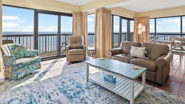 A spacious living area with a view of the ocean, featuring a sofa, armchair, and a coffee table. - Savoy 3BR Oceanfront Condo + Gym & Beach Access! | Savoy PH (Myrtle Beach)