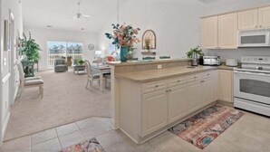 A modern kitchen with a central island, built-in appliances, and a view to the living area. - Modern Magnolia Pointe Condo Near Myrtle Beach | Magnolia Pointe Luster Leaf 4861-403 (Myrtle Beach)