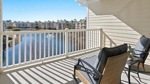 A balcony with a view of a water body and buildings in the background. - Modern Magnolia Pointe Condo Near Myrtle Beach | Magnolia Pointe Luster Leaf 4861-403 (Myrtle Beach)