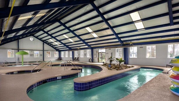 An indoor swimming pool with multiple lanes, a covered roof, and a seating area with chairs. - Modern Magnolia Pointe Condo Near Myrtle Beach | Magnolia Pointe Luster Leaf 4861-403 (Myrtle Beach)