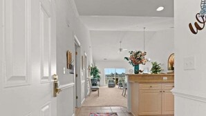 A hallway with a patterned rug, a wooden cabinet, and a vase with flowers. - Modern Magnolia Pointe Condo Near Myrtle Beach | Magnolia Pointe Luster Leaf 4861-403 (Myrtle Beach)