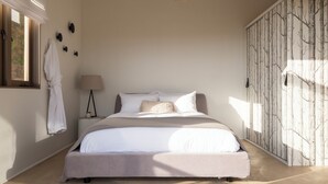 Une chambre avec un grand lit, un luminaire suspendu, une fenêtre avec vue et une armoire ornée d’un motif d’arbre.