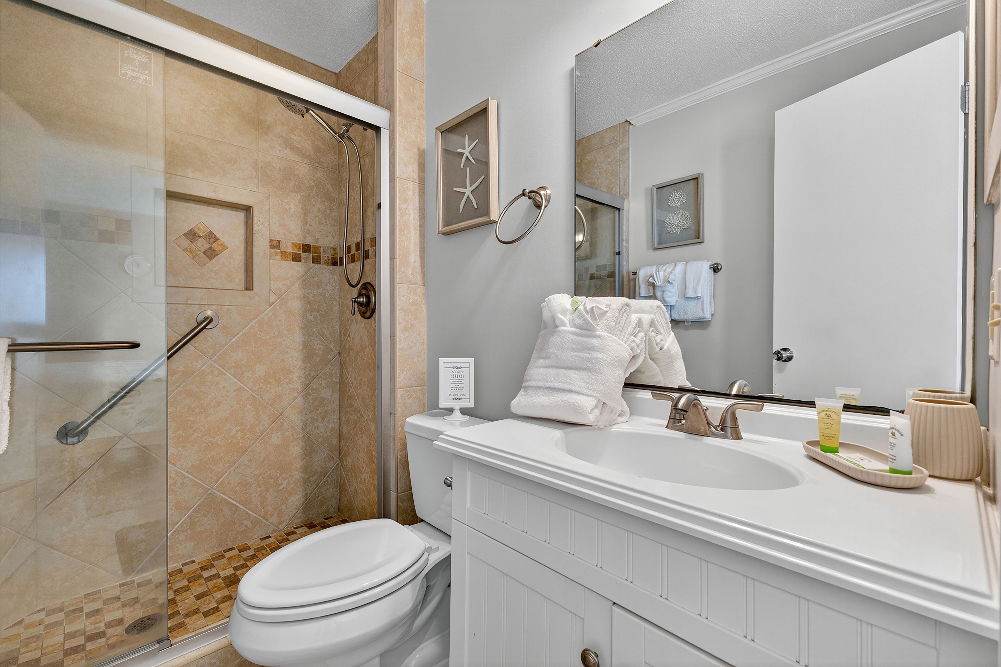 A modern bathroom with a glass shower enclosure, a white sink, and a large mirror.