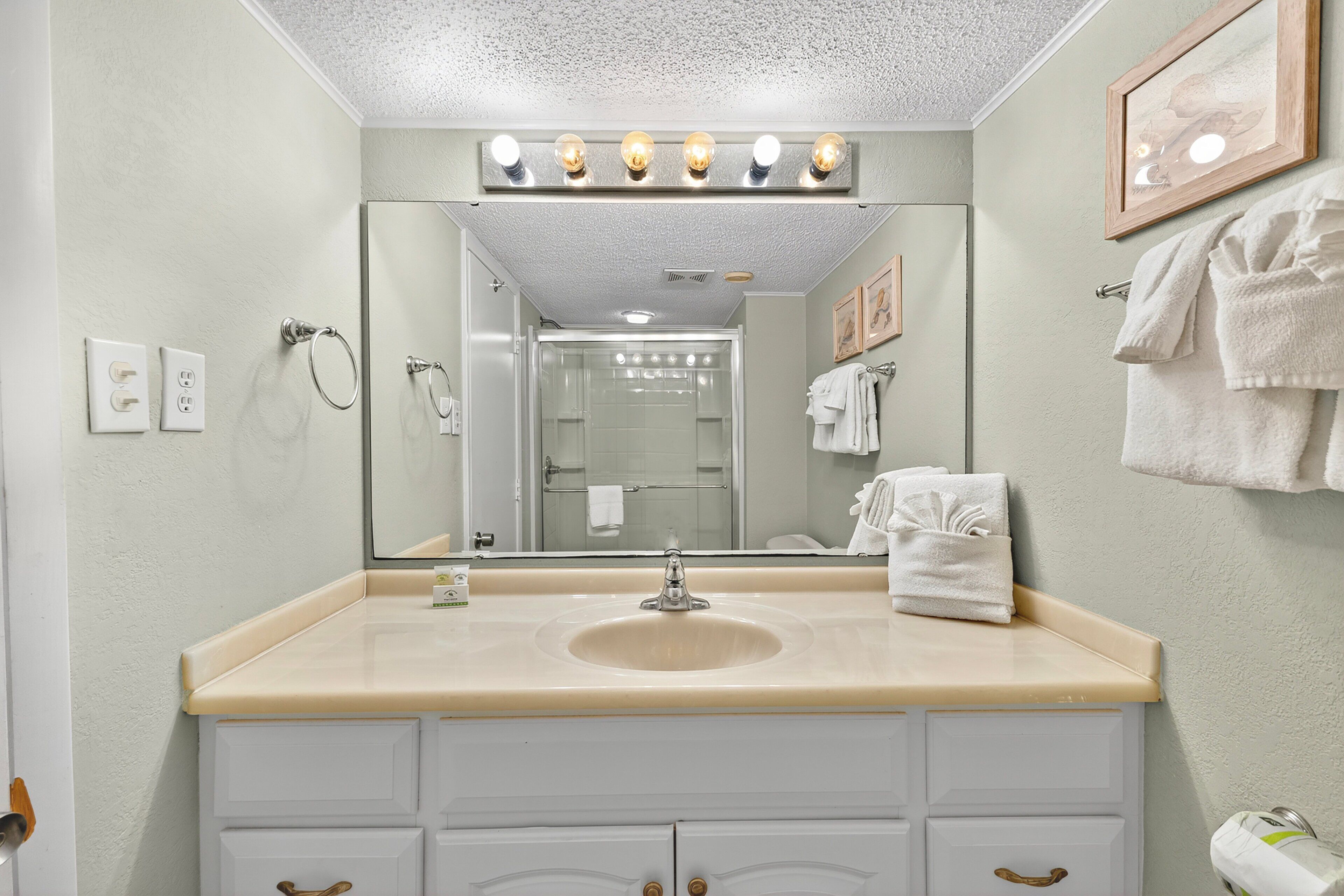 Un bagno con lavandino, specchio e portasciugamani.
