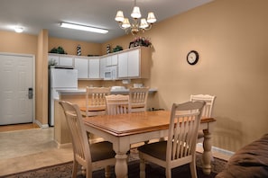 Cozy dining area with a wooden table and six chairs, surrounded by neutral walls and a clock on the wall.
