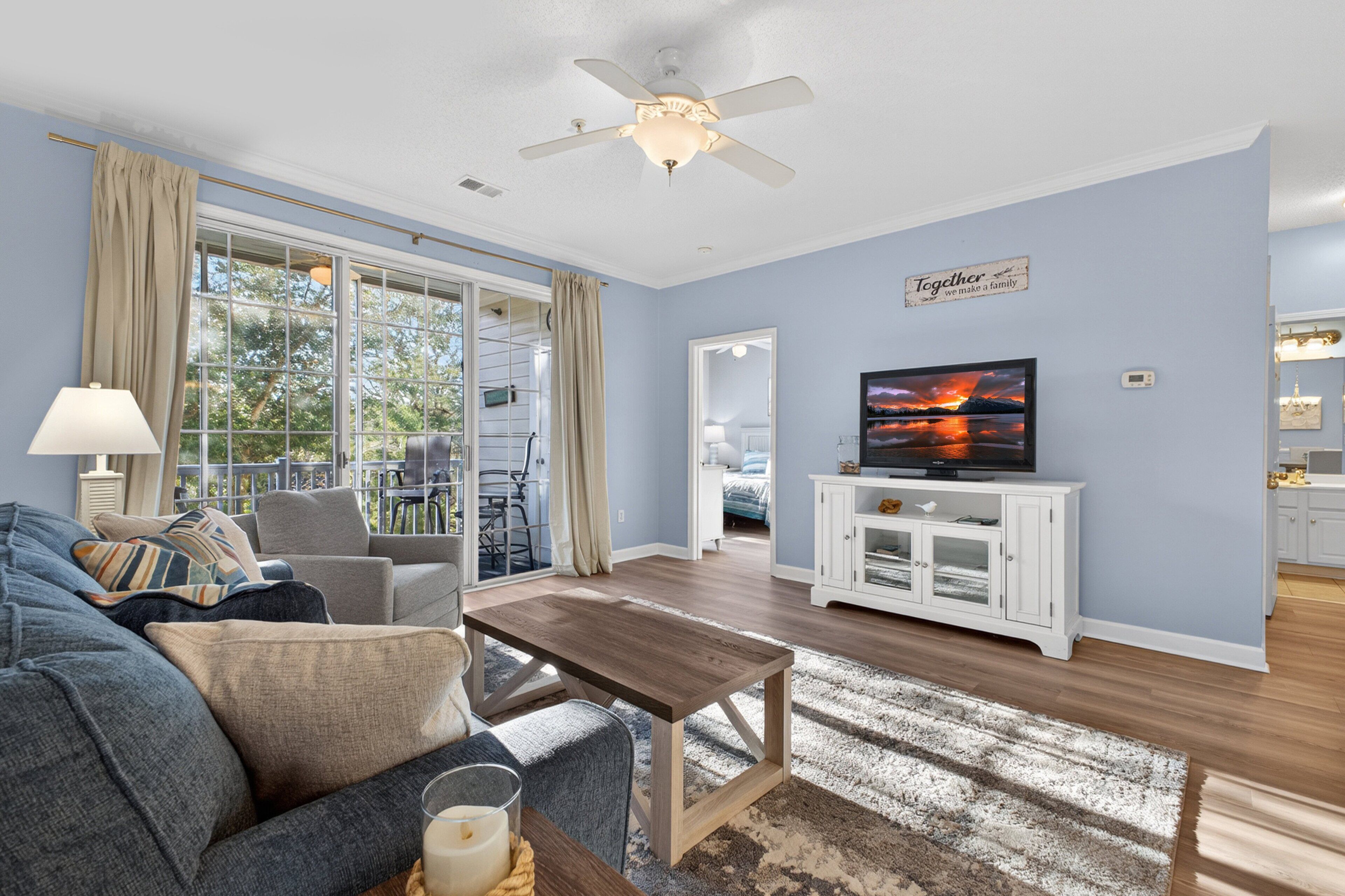 A living room with a sofa, coffee table, TV, and a ceiling fan.