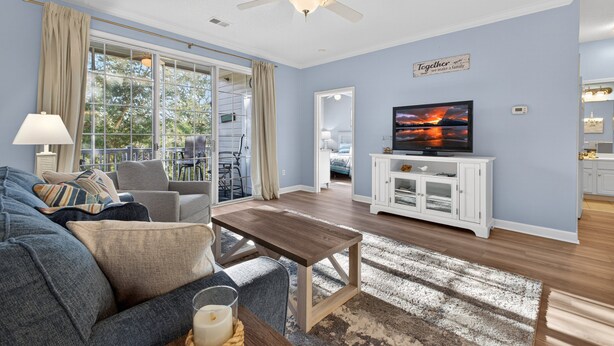 A living room with a sofa, coffee table, TV, and a ceiling fan.