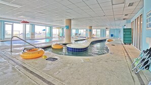 Une piscine intérieure dotée de plusieurs bains à remous et de bouées gonflables.