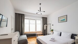 Moderni makuuhuone, jossa on suuri sänky, työpöytä ja ikkuna, jossa on verhot.