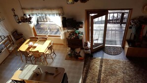 A spacious living area with a wooden dining table, a kitchen area with appliances, and a large sliding glass door leading to an outdoor deck.