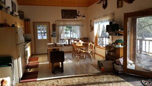 A cozy kitchen with wooden cabinets, a dining table with chairs, and a large window offering a view of a snowy landscape.