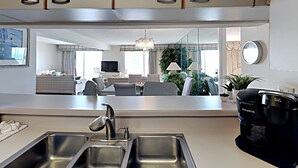 A modern kitchen with a built-in sink, a coffee maker, and a view into the living area. - Kingston Plantation South Hampton (Myrtle Beach)
