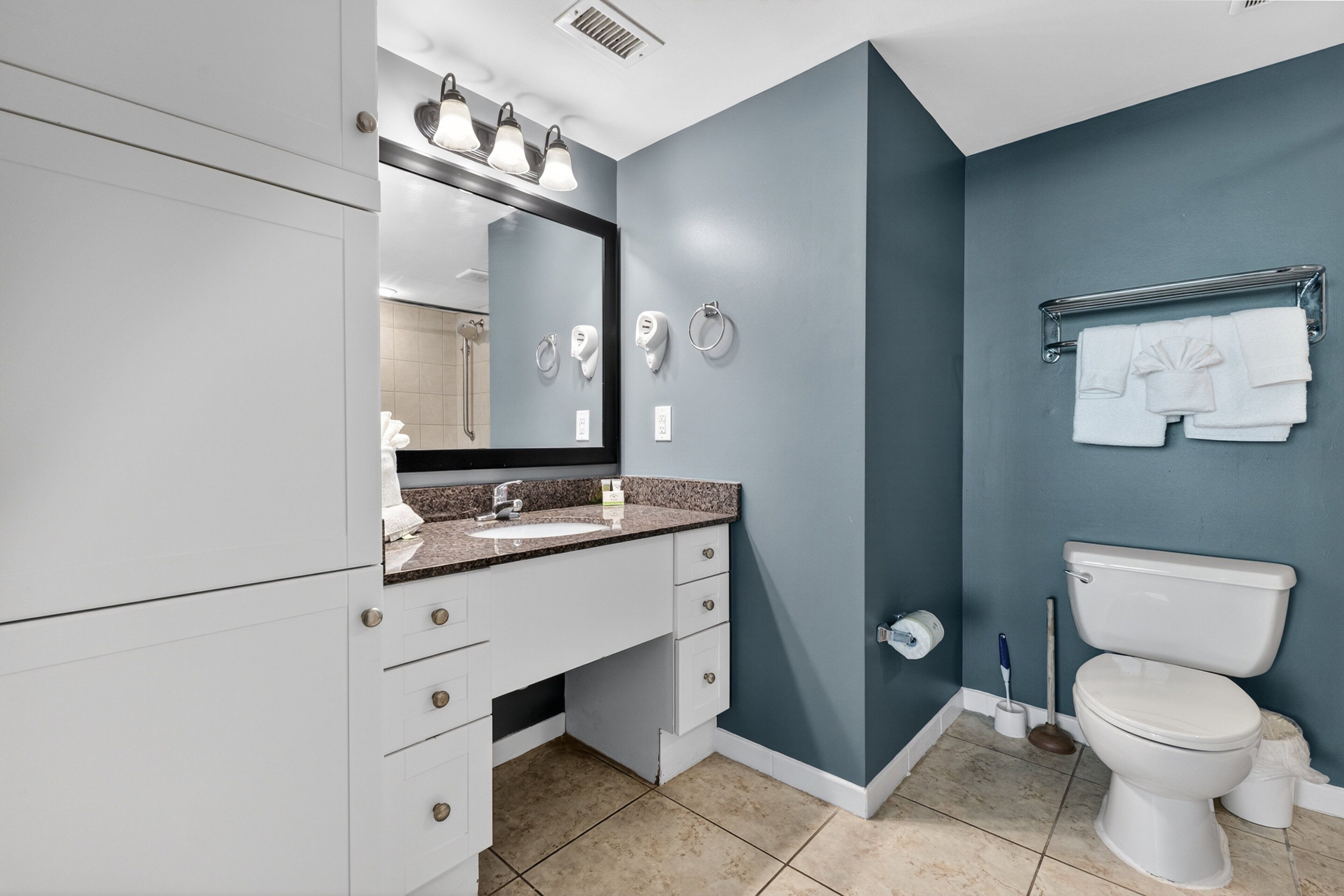 A modern bathroom with a white vanity, a sink, a mirror, and a toilet.