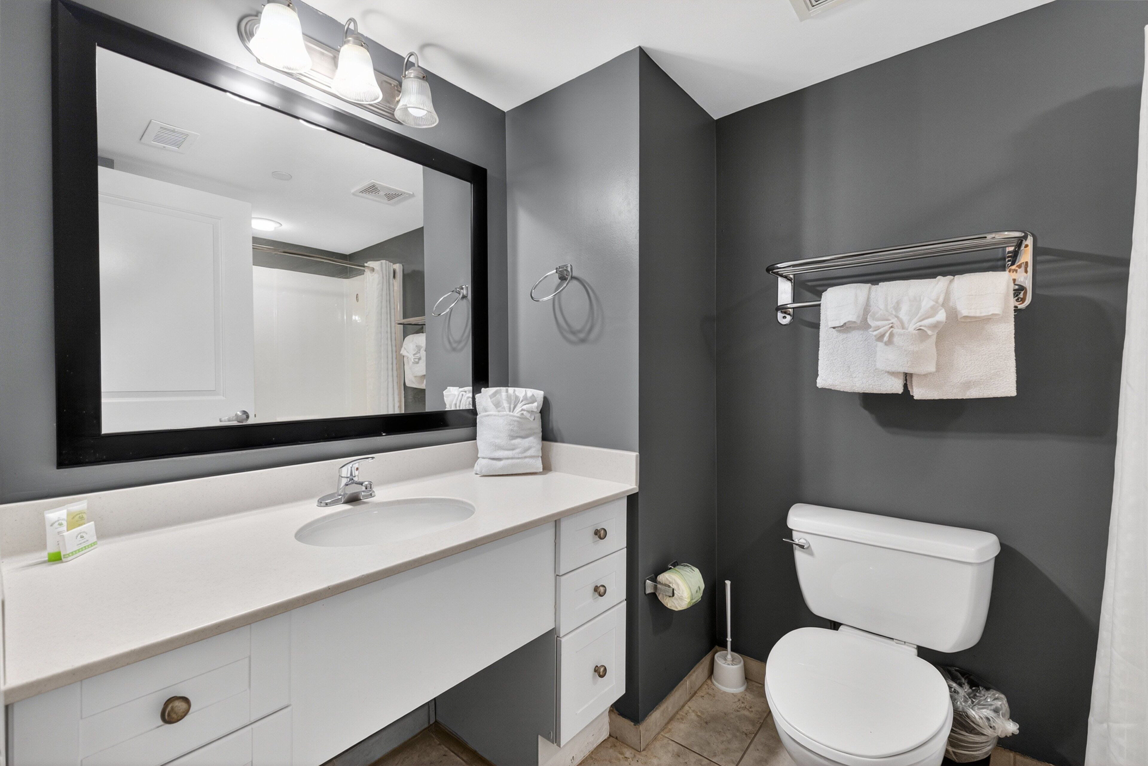 Un baño moderno con un lavabo blanco, un espejo grande, un toallero y un inodoro.