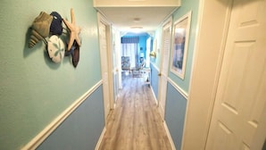 A hallway with a wooden floor, light blue walls, and a door on the right.
