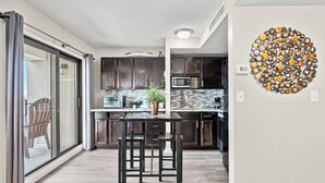 A modern kitchen with dark wood cabinets, a central island with stools, and a large decorative wall piece.