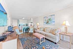 Uma sala de estar com sofá, cadeiras, mesa de centro e um espaço de refeições com cadeiras e uma mesa.